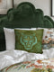 Square woven pillow featuring fierce turquoise tiger with bared fangs against olive green background surrounded by jungle leaves. Textured tapestry creates vibrant mid-century tiki decor perfect for rockabilly, maximalist room styling.