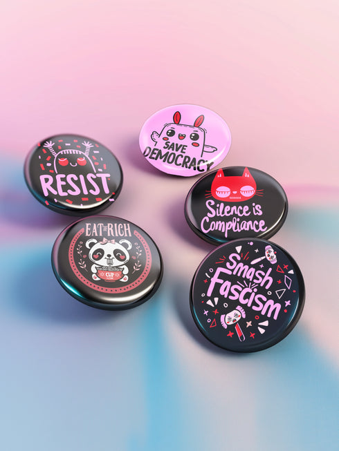 A set of five glossy round pinback buttons with pastel goth and kawaii punk designs, featuring slogans like "Eat The Rich" and "Smash Fascism" in bold pink and black. Each pin has a cute character delivering a powerful message.