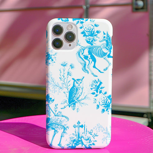 Phone case with a blue and white toile pattern featuring skeletons, owls, and floral motifs. Dual-layer protection available in glossy or matte finish.