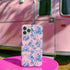 Phone case with pink background featuring blue toile print of skeletons, peacocks, owls, and roses. Victorian-inspired design with gothic elements. Dual-layer protection for various smartphone models.