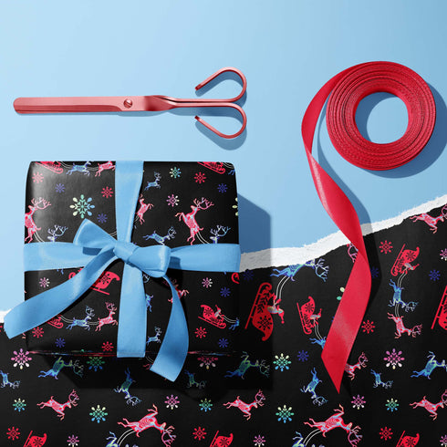 Christmas wrapping paper with a black background featuring colorful, stylized reindeer and Santa's sleigh designs. The reindeer and sleigh silhouettes are filled with skeletal patterns in shades of blue, pink, and red. Multicolored snowflakes in various sizes are scattered throughout. The paper has a whimsical, slightly gothic aesthetic that blends traditional holiday imagery with a unique, edgy twist.
