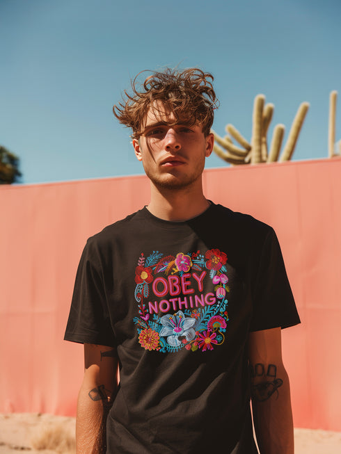 Black activist T-shirt with a floral embroidered-style design and the words “Obey Nothing” in bold, bright lettering.