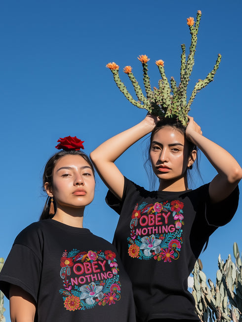 Black activist T-shirt with a floral embroidered-style design and the words “Obey Nothing” in bold, bright lettering.