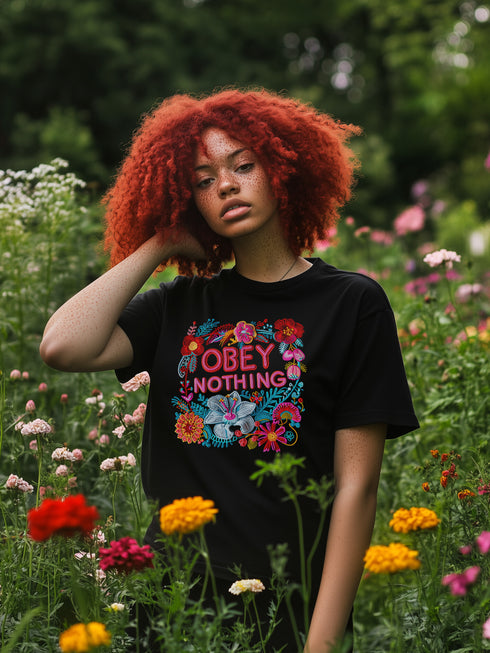 Black activist T-shirt with a floral embroidered-style design and the words “Obey Nothing” in bold, bright lettering.