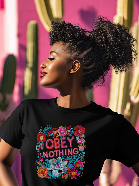 Black activist T-shirt with a floral embroidered-style design and the words “Obey Nothing” in bold, bright lettering.