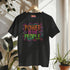 Black unisex t-shirt with colorful "POWER TO THE PEOPLE" text design in orange, pink, and green lettering surrounded by swirling psychedelic rainbow border.