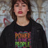 Black unisex t-shirt with colorful "POWER TO THE PEOPLE" text design in orange, pink, and green lettering surrounded by swirling psychedelic rainbow border.