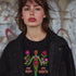 Black unisex t-shirt with "MY BODY MY RIGHTS" design featuring neon green female figure filled with vibrant pink and red flowers. Feminist pro-choice shirt with colorful text, available in cotton-poly blend, sizes S-3XL.
