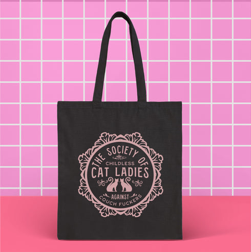 Election 2024 Canvas tote bag featuring a circular design with two cats and text "The Society of Childless Cat Ladies Against Couch Fuckers" in burgundy on a natural or black.