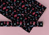 Christmas wrapping paper with a black background featuring colorful, stylized reindeer and Santa's sleigh designs. The reindeer and sleigh silhouettes are filled with skeletal patterns in shades of blue, pink, and red. Multicolored snowflakes in various sizes are scattered throughout. The paper has a whimsical, slightly gothic aesthetic that blends traditional holiday imagery with a unique, edgy twist.