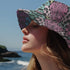 Reversible bucket hat with colorful snakeskin print in pastel shades of pink, blue, and yellow