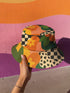Reversible unisex bucket hat featuring two distinct retro-inspired designs - one side showcases a vibrant 70s-style floral pattern with large orange and yellow flowers, green leaves, and black polka dot accents on cream and coral backgrounds, while the reverse side displays a sophisticated brown and beige floral pattern with orange blooms and neutral tones. Made from 100% polyester with textured linen feel, this moisture-wicking and breathable hat is available in XS, S/M, and L/XL sizes, perfect for vintage
