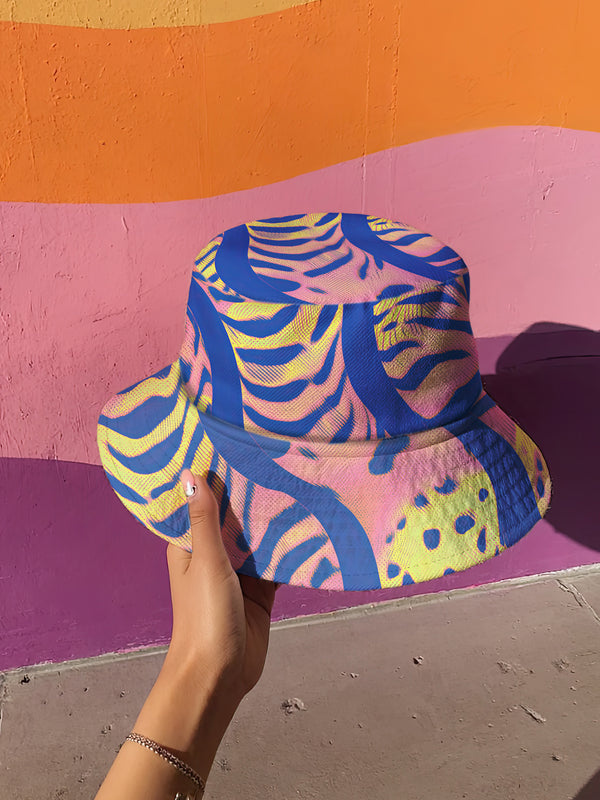 Reversible bucket hat with a bold all-over psychedelic tiger stripe print in pink, blue, yellow, and black; made of moisture-wicking polyester with a linen-texture feel; available in sizes XS, S/M, and L/XL; features two different sides with unique patterns.