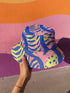 Reversible bucket hat with a bold all-over psychedelic tiger stripe print in pink, blue, yellow, and black; made of moisture-wicking polyester with a linen-texture feel; available in sizes XS, S/M, and L/XL; features two different sides with unique patterns.