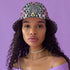 Reversible bucket hat with colorful snakeskin print in pastel shades of pink, blue, and yellow