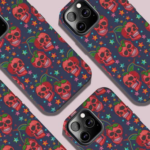 Phone case featuring vibrant red apple skulls with green stems and multicolored stars on navy background. Gothic alternative design with bright colorful accents.
