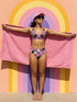 Two piece pastel goth bikini with a v neck top and high waisted bottom. The purple top is covered in large black cherries dripping red, tiny flying bats, and white sparkle stars. The high cut bottoms show a pink, lavender, black, and cream checkerboard overlaid with black thorny vines and dripping red hearts. Soft, stretchy recycled polyester fabric with UPF 50 sun protection and removable padding. Creepy cute whimsigoth swimwear for spooky summer pool days, haunted beach trips, and music festivals.
