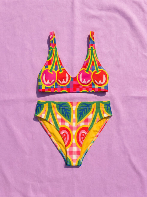 Vibrant two piece maximalist bikini with a v neck bralette top and high waisted bottom. The fabric mixes a bright yellow and hot pink gingham checkerboard with oversized neon pink and red cherries, green leaves, and semicircle watermelon shapes with white dots along the lower edge. Smooth, stretchy recycled polyester with UPF 50 sun protection and removable padding. Bold retro pop art swimwear in saturated dopamine colors, built for pool parties, vacation outfits, and fun beach days.