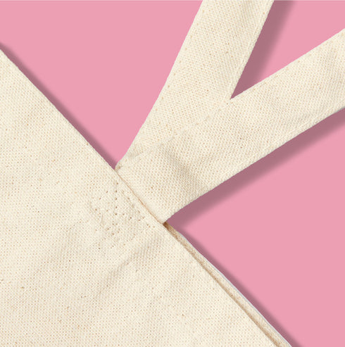 Canvas tote bag featuring pink skull cherries design. Two pink skulls connected by red stem and bow. Quirky gothic-inspired graphic on cream background. Stylish, edgy accessory for everyday use. Perfect for alternative fashion lovers.