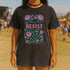 Comfort Colors 1717 unisex garment-dyed t-shirt featuring a front floral graphic with the word RESIST in pink block letters surrounded by green vines, purple roses, skulls, moons, and daggers. Made of soft-washed 100% ring-spun cotton with tubular knit construction, available in sizes S to 4XL.
