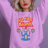 A Christmas sweatshirt featuring a playful design with a cartoon Baphomet goat character wearing a Santa hat. The design includes the text "All Hail Santa" above the goat, with pentagrams in flames on either side. The goat is depicted in a meditative pose, adding a humorous and irreverent twist to holiday attire.