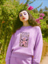 Comfort Colors garment-dyed sweatshirt featuring 'Patriarchy Slayer' design with pink armored knight holding sword and banner reading 'Burn It Down', surrounded by decorative floral border with roses and leaves. Made from 80% ring-spun cotton and 20% polyester with relaxed fit and rolled-forward shoulders. Available in lavender purple and seafoam green colorways, sizes S-3XL unisex, featuring sustainable made-to-order production with OEKO-TEX certified low-impact dyes and zero waste manufacturing process.