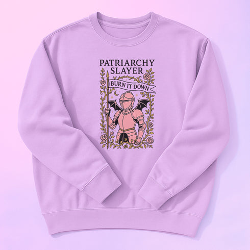 Comfort Colors garment-dyed sweatshirt featuring 'Patriarchy Slayer' design with pink armored knight holding sword and banner reading 'Burn It Down', surrounded by decorative floral border with roses and leaves. Made from 80% ring-spun cotton and 20% polyester with relaxed fit and rolled-forward shoulders. Available in lavender purple and seafoam green colorways, sizes S-3XL unisex, featuring sustainable made-to-order production with OEKO-TEX certified low-impact dyes and zero waste manufacturing process.