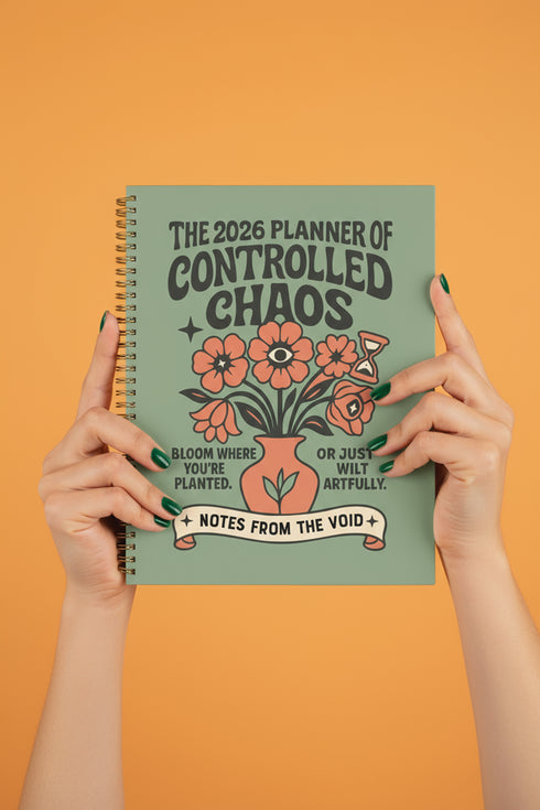 A sage green hardcover spiral planner for 2026 with the title "The 2026 Planner of Controlled Chaos" in a funky, retro 70s-style font. The cover features a groovy illustration of orange and pink flowers in a vase, with one flower depicted as an eyeball. The text reads "Bloom where you're planted. Or just wilt artfully." and "Notes from the Void." The planner has a gold metal wire-o binding. The back cover shows a decorative floral frame with a "Property Of" section
