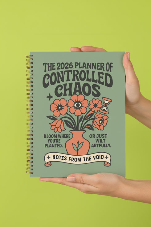 A sage green hardcover spiral planner for 2026 with the title "The 2026 Planner of Controlled Chaos" in a funky, retro 70s-style font. The cover features a groovy illustration of orange and pink flowers in a vase, with one flower depicted as an eyeball. The text reads "Bloom where you're planted. Or just wilt artfully." and "Notes from the Void." The planner has a gold metal wire-o binding. The back cover shows a decorative floral frame with a "Property Of" section