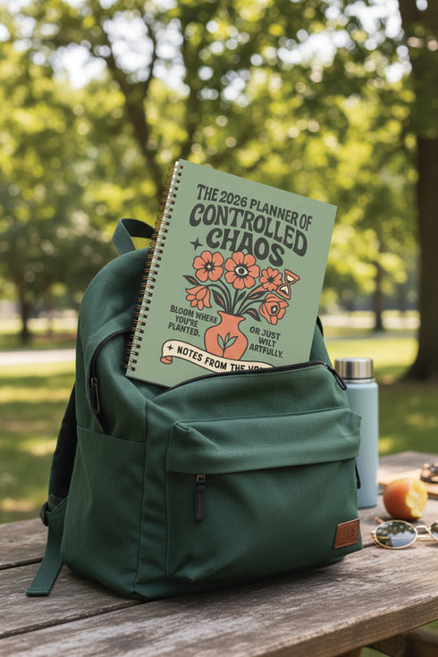 A sage green hardcover spiral planner for 2026 with the title "The 2026 Planner of Controlled Chaos" in a funky, retro 70s-style font. The cover features a groovy illustration of orange and pink flowers in a vase, with one flower depicted as an eyeball. The text reads "Bloom where you're planted. Or just wilt artfully." and "Notes from the Void." The planner has a gold metal wire-o binding. The back cover shows a decorative floral frame with a "Property Of" section