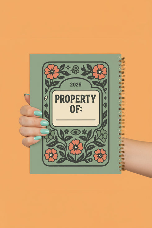 A sage green hardcover spiral planner for 2026 with the title "The 2026 Planner of Controlled Chaos" in a funky, retro 70s-style font. The cover features a groovy illustration of orange and pink flowers in a vase, with one flower depicted as an eyeball. The text reads "Bloom where you're planted. Or just wilt artfully." and "Notes from the Void." The planner has a gold metal wire-o binding. The back cover shows a decorative floral frame with a "Property Of" section