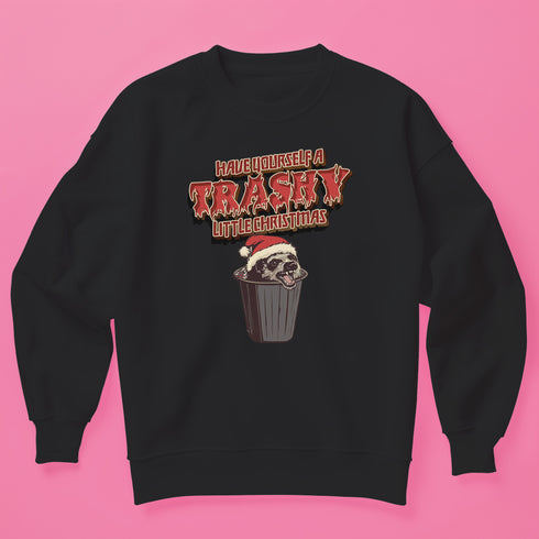 Holiday jumper sweatshirt with "HAVE YOURSELF A TRASHY LITTLE CHRISTMAS" text above a possum wearing a Santa hat, peeking out of a garbage can. Bold, punk-style lettering in red and yellow.