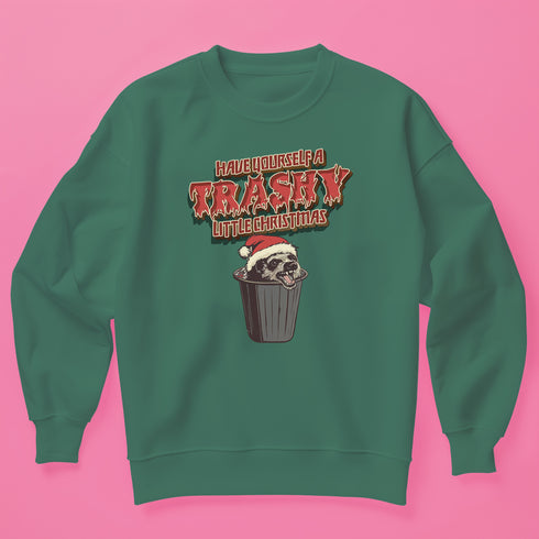 Holiday jumper sweatshirt with "HAVE YOURSELF A TRASHY LITTLE CHRISTMAS" text above a possum wearing a Santa hat, peeking out of a garbage can. Bold, punk-style lettering in red and yellow.