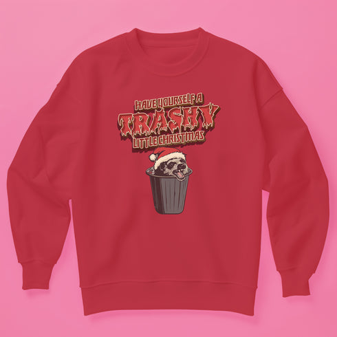 Holiday jumper sweatshirt with "HAVE YOURSELF A TRASHY LITTLE CHRISTMAS" text above a possum wearing a Santa hat, peeking out of a garbage can. Bold, punk-style lettering in red and yellow.
