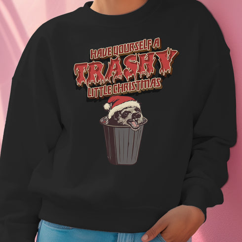 Holiday jumper sweatshirt with "HAVE YOURSELF A TRASHY LITTLE CHRISTMAS" text above a possum wearing a Santa hat, peeking out of a garbage can. Bold, punk-style lettering in red and yellow.