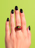 A red enamel Evil Eye Signet Ring with gold plating and zircon gemstone center, shown on a model’s hand with red nails. The ring’s symbolic design represents protection and empowerment. Bright yellow backdrop for modern maximalist appeal.