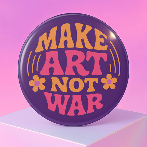A round, glossy purple pinback button with the words "MAKE ART NOT WAR" in a groovy, retro 70s-style font. The word "MAKE" is in orange, "ART" is in a vibrant pink, and "NOT WAR" is in orange. The text is surrounded by small, stylized flower and star details. This psychedelic protest pin is a piece of activist merch with a strong metal back and safety pin clasp, perfect as an anti-war or social justice accessory for a jean jacket or backpack. The pin has a handmade, indie aesthetic.