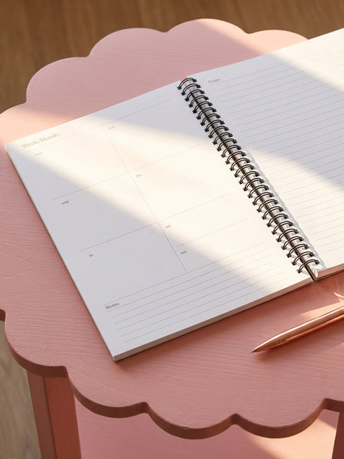 Undated weekly planner with hardcover and metal wire-o spiral binding options in black or gold. Cover features retro pop art illustration of a three-eyed woman crying while holding wine and tissues, with text Scheduled Hysteria. Vibrant orange background with psychedelic blue and purple patterns. Open planner shows flexible weekly layout on high-quality 60lb paper. Lays flat for easy writing. Ideal for ADHD organization, funny mental health gifts, and maximalist desk decor. Satin matte finish.