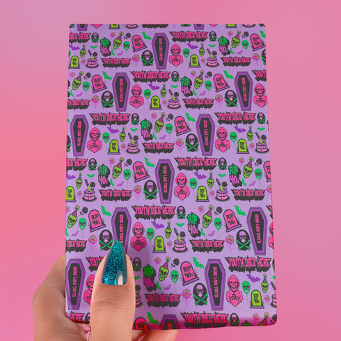 Vibrant purple wrapping paper with gothic-inspired design for 50th birthdays. Features colorful skulls wearing party hats, coffins, 'RIP 40s' tombstones, and 'Youth Dies Here' text. Perfect for edgy, humorous gifts to 50-year-olds.