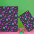 Spooky birthday wrapping paper with neon pink skulls, blue coffins, eyeballs, and bats on black background. Vibrant and gothic design for unique gift presentation.