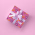 Vibrant pink wrapping paper featuring Occult symbol Baphomet Santas throwing horns, surrounded by flaming pentagrams and "All Hail Santa" text. A punk rock twist on Christmas gift wrap.