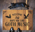 Tan coir doormat featuring "Welcome, Hope You Like Goth Music" in black text, with bat and skull imagery and gothic-style corner decorations.