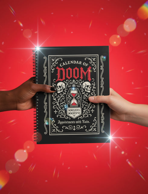 An 8.5 x 11 inch black hardcover spiral planner with a durable satin matte laminated finish. The front cover features a vintage-style white ornamental border, creating a gothic, macabre aesthetic. Inside the frame, the title "Calendar of Doom" is printed in an antique serif font. This undated weekly and monthly agenda is shown with a metal wire-o spiral binding on the right side. The design uses a black, white, and red color scheme, making it a unique piece of dark humor stationery