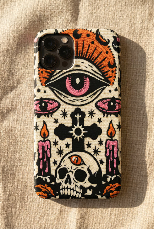 A vertical phone case design featuring a faux crochet texture illusion printed on a cream background. The symmetrical pattern centers on a large black eye with a pink iris and rust-orange sunburst lashes at the top. Below the eye is a black cross surrounded by small black stars. The bottom features a skull with a third rust-orange eye on its forehead. Flanking the skull are two candles with orange flames and rust-colored leaves. The design mimics the look of stitched yarn but is a 2d print.