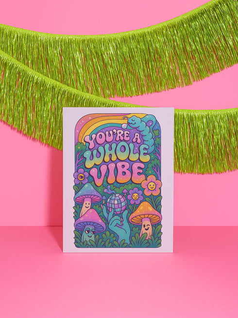 5x7 inch greeting card featuring colorful psychedelic artwork with smiling mushrooms, pastel rainbow, disco ball, flowers, and a blue slug. The inside reads: “Keep blooming, keep weirding. You’re exactly the kind of strange this world needs.” Printed on silk cover stock with a soft glossy finish and includes a white envelope