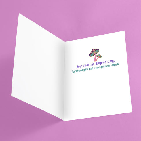 5x7 inch greeting card featuring colorful psychedelic artwork with smiling mushrooms, pastel rainbow, disco ball, flowers, and a blue slug. The inside reads: “Keep blooming, keep weirding. You’re exactly the kind of strange this world needs.” Printed on silk cover stock with a soft glossy finish and includes a white envelope