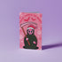 Quirky Christmas card featuring grim reaper in Santa hat. Pink background with bats, snowflakes, skull motifs. Text reads 'Grave Tidings We Bring'. Humorous blend of holiday cheer and gothic aesthetic. Perfect for alternative Christmas greetings.