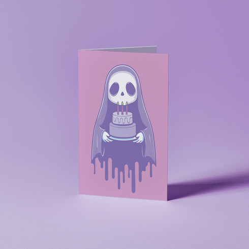 Birthday card featuring a cute cartoon grim reaper holding a birthday cake on pink background. The reaper wears a purple cloak and has a white skull face. It's carrying a small purple cake with three lit candles. The reaper's cloak drips like melting icing at the bottom. Ideal for Halloween birthdays or gothic-themed celebrations. Inside greeting: "Hope your B-day is spooky AF and sweet as cake!"