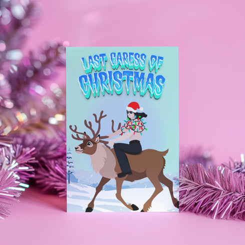 A humorous holiday card featuring an illustration of Glenn Danzig from the Misfits riding a reindeer, wearing a Santa hat and wrapped in Christmas lights. The text at the top reads "Last Caress of Christmas" in icy blue letters, referencing the iconic Misfits song. The background depicts a snowy winter scene, combining punk rock and festive elements for a playful twist.