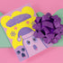 Christmas card with a playful ghost theme. Central cute pink ghost wearing a purple Santa hat, flanked by two smaller purple ghosts. Yellow background with snowflakes. Text reads "Boo HUMBUG" in purple bubble letters. Blends Christmas and Halloween elements for a unique holiday greeting. Inside message: "May your Christmas be filled with delight, not fright.